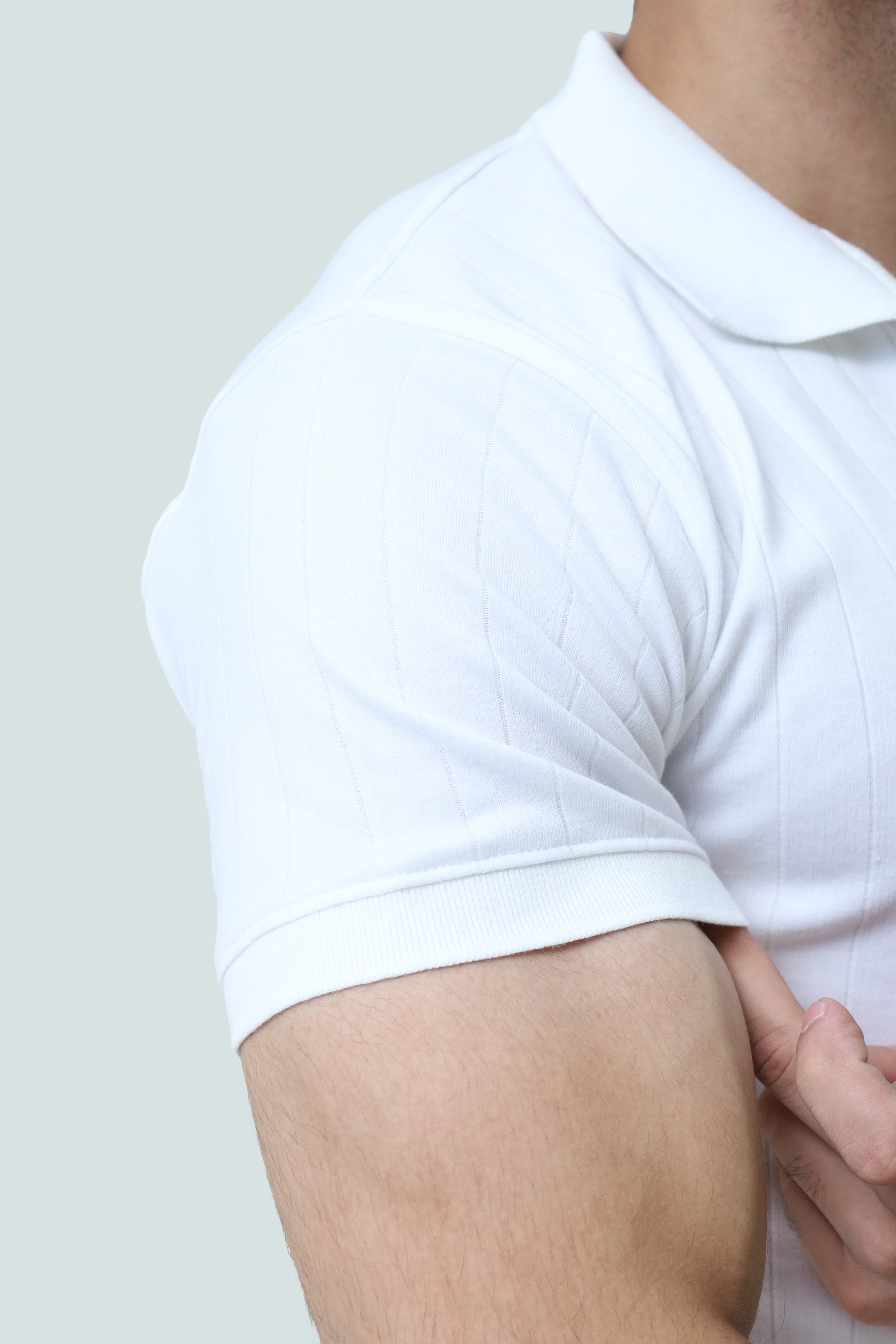 White cable-knit polo shirt from theseventhstitch with a classic collar and textured knit design, displayed on a flat surface.